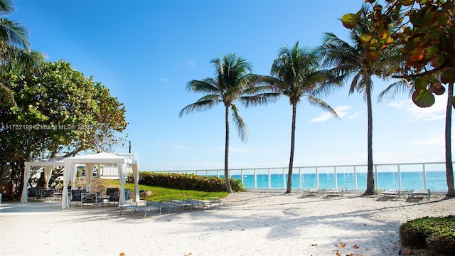 property view of water with fence, a beach view, and a gazebo