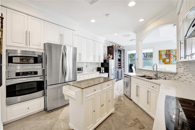 1468 Mariner Way, Hollywood, FL 33019 - kitchen with stainless steel appliances, crown molding, arched walkways, decorative backsplash, and light stone counters