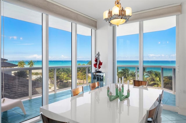 dining room with plenty of natural light, floor to ceiling windows, a water view, and an inviting chandelier