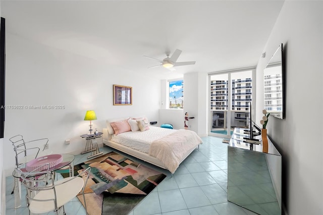 tiled bedroom with a ceiling fan, access to exterior, and a wall of windows