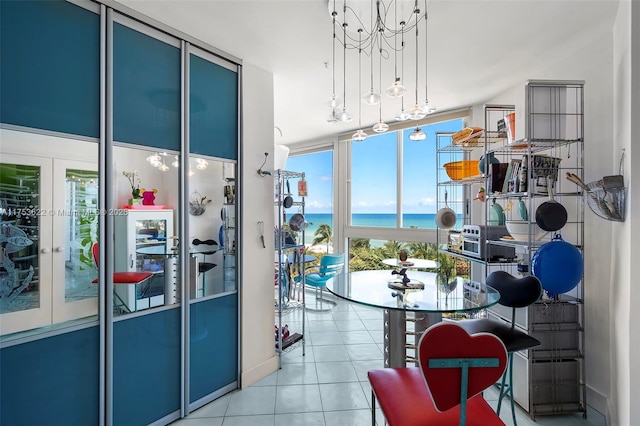 interior space with tile patterned flooring, floor to ceiling windows, a water view, and an inviting chandelier