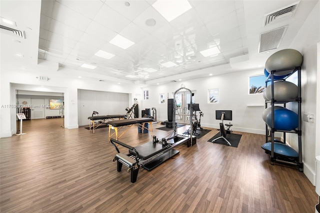 workout area featuring a paneled ceiling, baseboards, visible vents, and wood finished floors