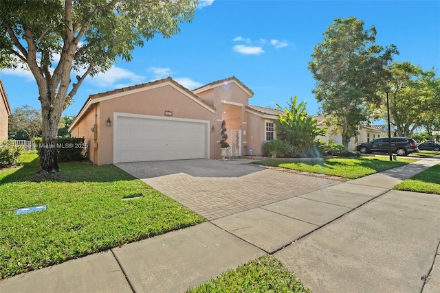 view of front of property featuring an attached garage, decorative driveway, a front yard, and stucco siding