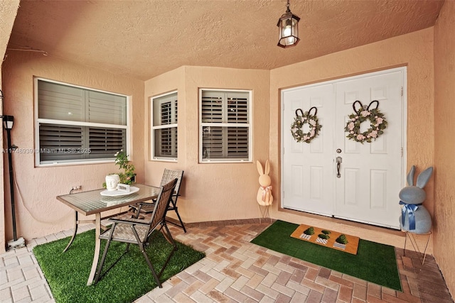 property entrance with a patio area, outdoor dining area, and stucco siding