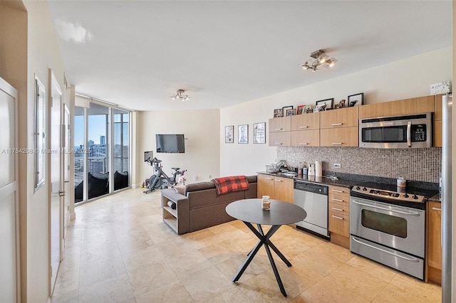 kitchen featuring floor to ceiling windows, dark countertops, backsplash, appliances with stainless steel finishes, and open floor plan