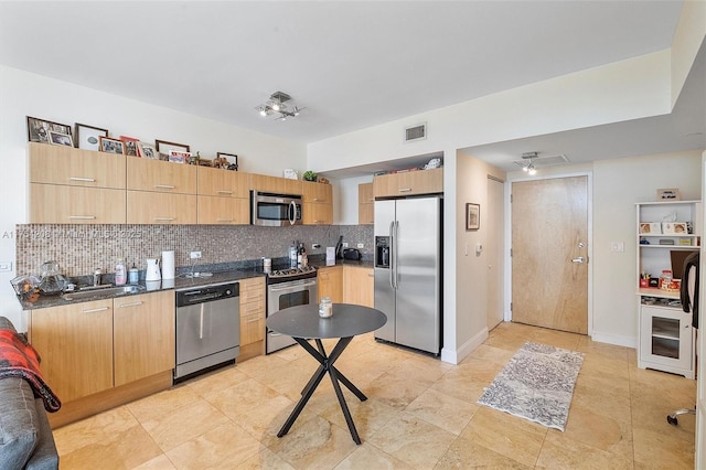 kitchen with tasteful backsplash, visible vents, dark countertops, stainless steel appliances, and a sink