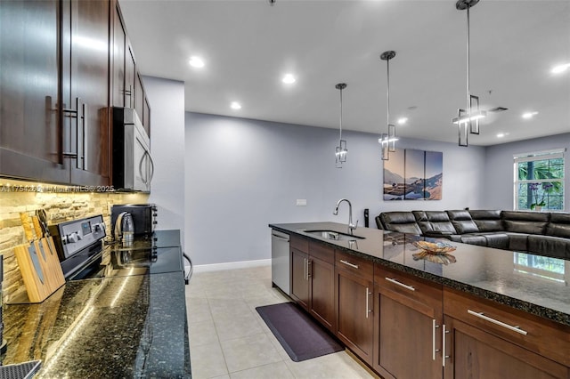 kitchen featuring dark stone counters, appliances with stainless steel finishes, a sink, backsplash, and light tile patterned flooring