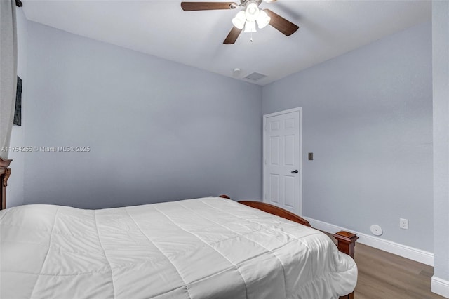 bedroom with ceiling fan, wood finished floors, visible vents, and baseboards