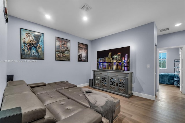 living room with wood finished floors, visible vents, and baseboards