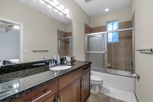 full bathroom featuring ensuite bathroom, toilet, bath / shower combo with glass door, vanity, and tile patterned floors