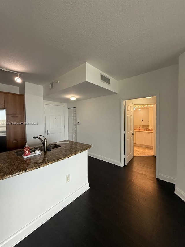 kitchen featuring dark wood-type flooring, visible vents, a sink, and baseboards