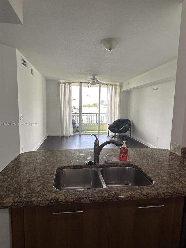 kitchen featuring dark stone counters, open floor plan, a sink, and floor to ceiling windows