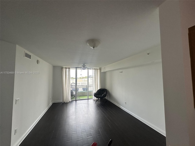 interior space featuring expansive windows, dark wood-style floors, visible vents, and baseboards