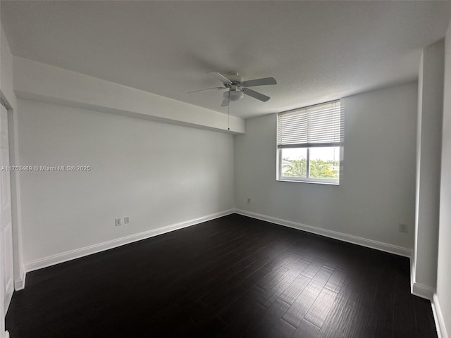 spare room with ceiling fan, baseboards, and dark wood finished floors