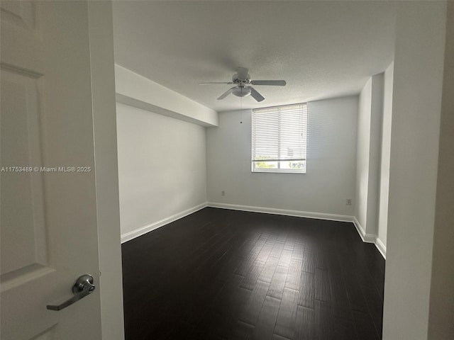 empty room with ceiling fan, baseboards, and dark wood-type flooring