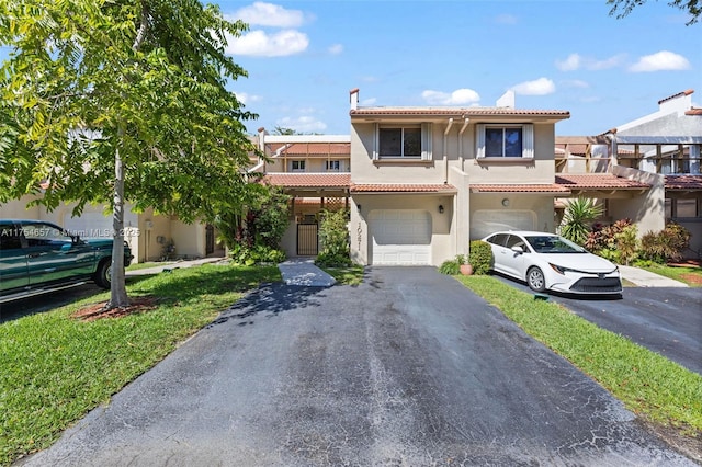 view of front of house featuring a garage, stucco siding, aphalt driveway, and a tiled roof