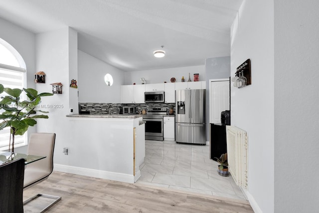 4331 SW 160th Ave Unit 108, Miramar, FL 33027 - kitchen with appliances with stainless steel finishes, white cabinetry, decorative backsplash, a peninsula, and baseboards