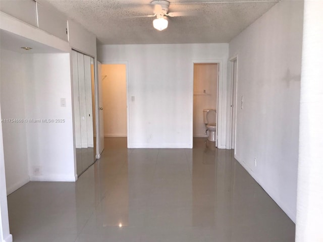 empty room with ceiling fan, concrete floors, and a textured ceiling