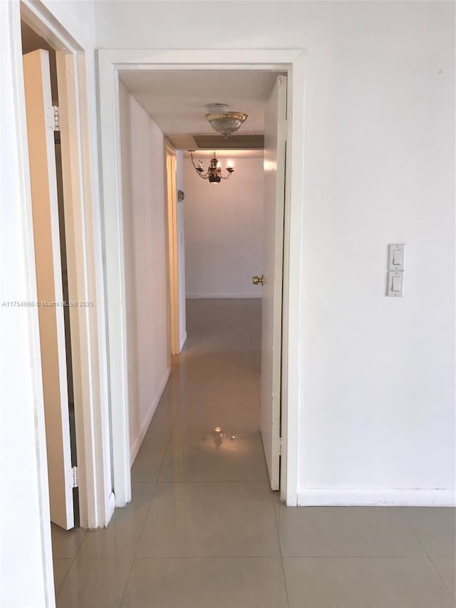 hall featuring tile patterned flooring and baseboards