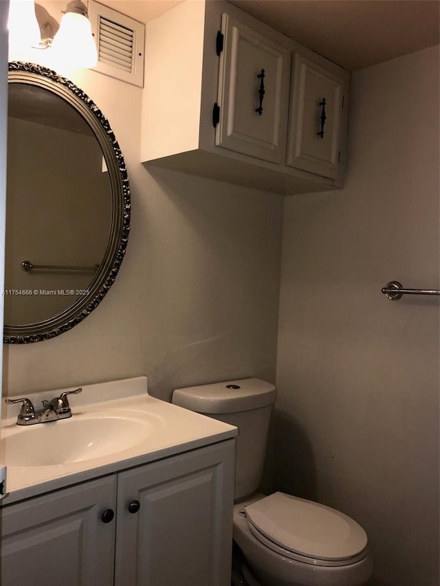 half bath featuring visible vents, vanity, and toilet