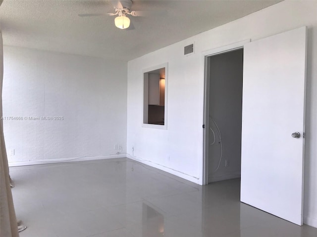 empty room featuring a textured ceiling, ceiling fan, visible vents, and tile patterned floors