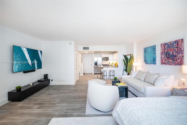 living room featuring light wood-type flooring, baseboards, and visible vents