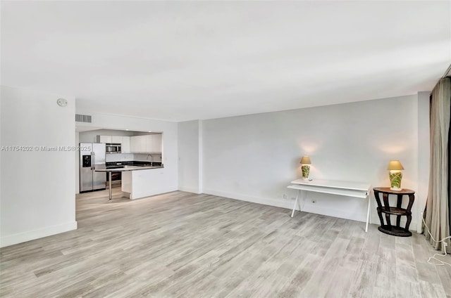 living area featuring light wood-style floors, visible vents, and baseboards