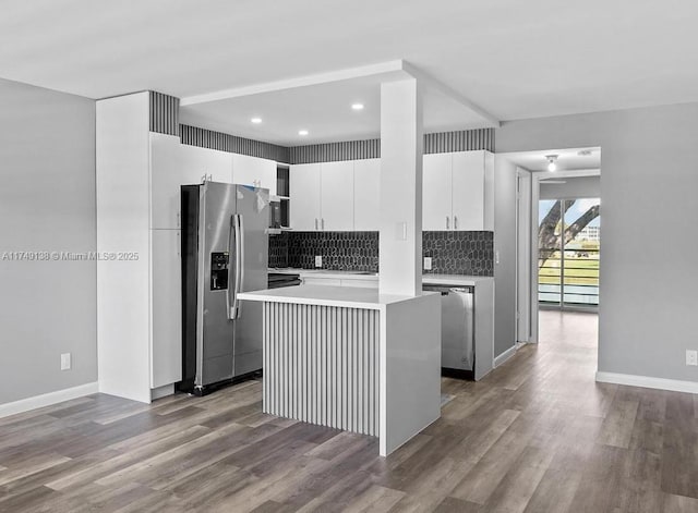 kitchen featuring tasteful backsplash, stainless steel appliances, wood finished floors, and a center island