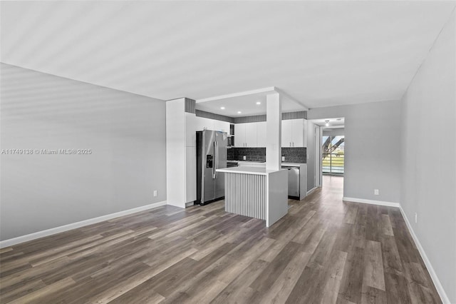 kitchen with decorative backsplash, appliances with stainless steel finishes, dark wood-style flooring, a center island, and light countertops