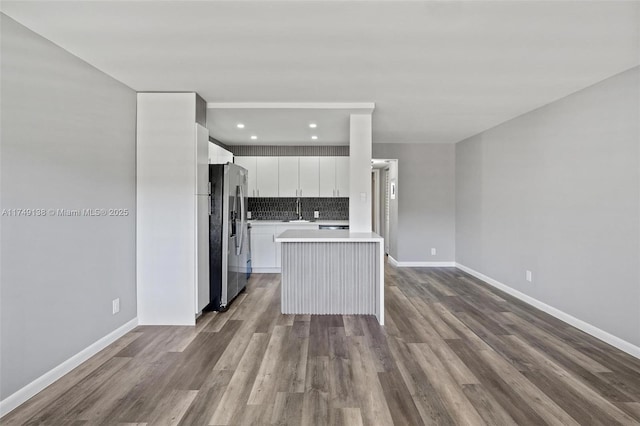 kitchen with white cabinets, dark wood-style floors, light countertops, stainless steel refrigerator with ice dispenser, and backsplash