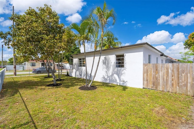 exterior space featuring stucco siding, fence, and a yard