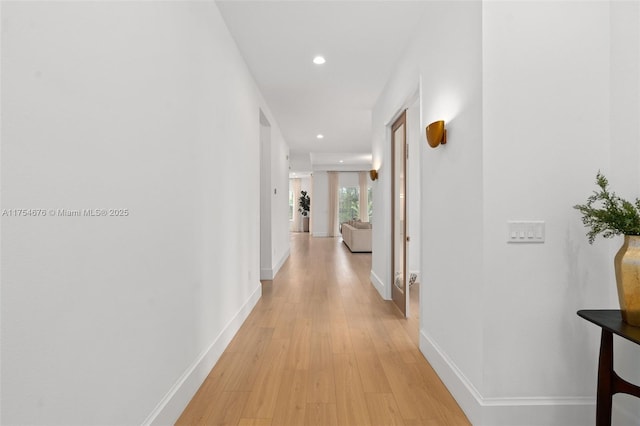 corridor featuring light wood-type flooring, baseboards, and recessed lighting