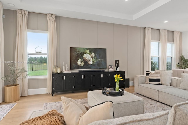 living room featuring plenty of natural light, wood finished floors, and a decorative wall