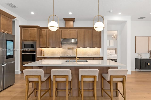 kitchen featuring a sink, under cabinet range hood, stainless steel appliances, and backsplash