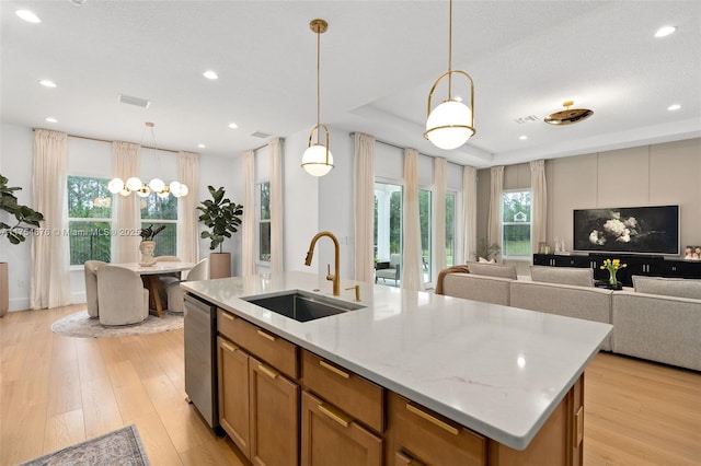 kitchen featuring open floor plan, a sink, an island with sink, and light wood finished floors