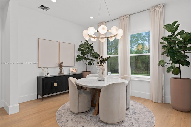 dining space with light wood-style flooring, visible vents, and baseboards