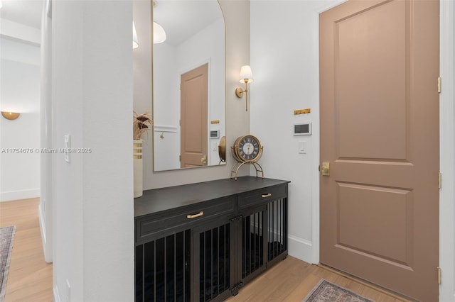 interior space featuring arched walkways, light wood-style flooring, and baseboards