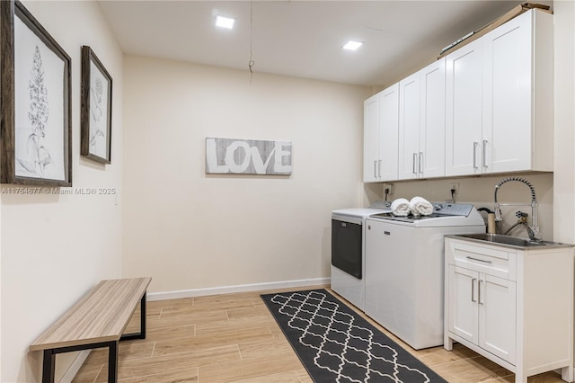 laundry room with wood tiled floor, cabinet space, a sink, and separate washer and dryer