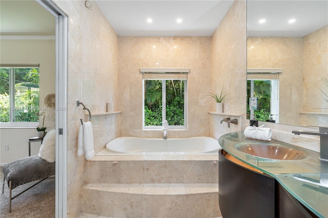 full bathroom featuring a wealth of natural light, recessed lighting, vanity, and a garden tub