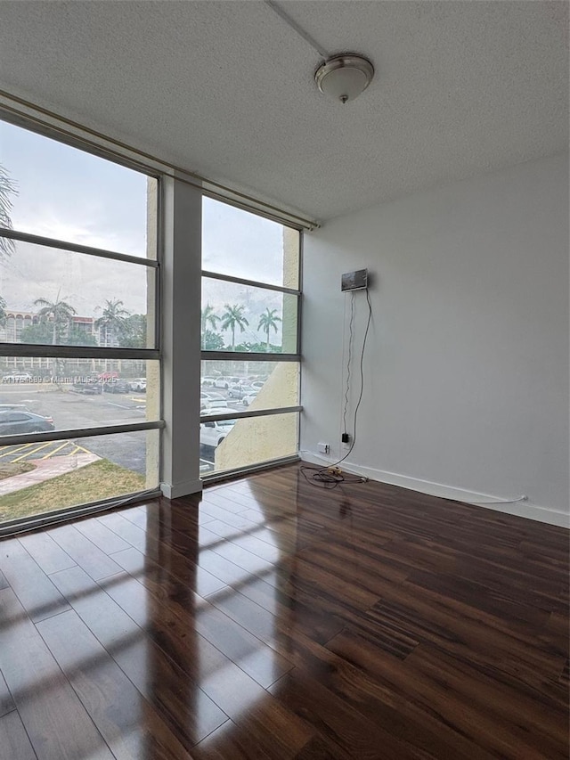 851 Three Islands Blvd Unit 218, Hallandale Beach, FL 33009 - spare room with wood finished floors, floor to ceiling windows, a textured ceiling, and baseboards