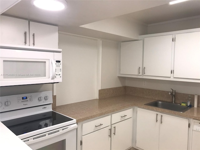 kitchen with white appliances, white cabinets, a sink, and light countertops