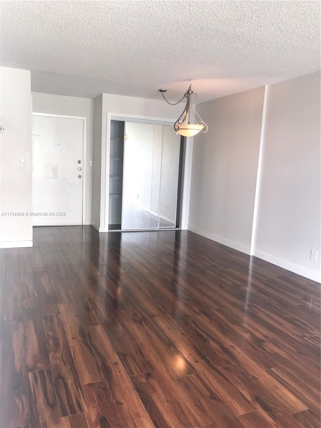 empty room with a textured ceiling, baseboards, and wood finished floors