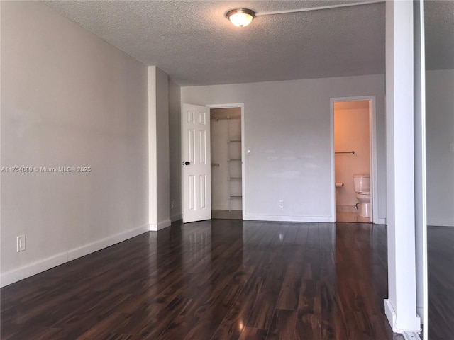 spare room featuring a textured ceiling, baseboards, and dark wood-style flooring