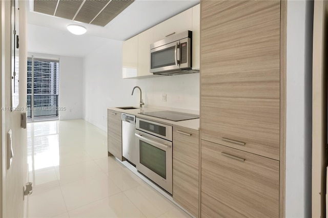 kitchen featuring visible vents, modern cabinets, appliances with stainless steel finishes, light countertops, and a sink