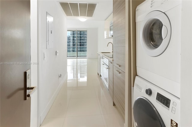 laundry room featuring light tile patterned floors, a sink, visible vents, baseboards, and stacked washer / drying machine