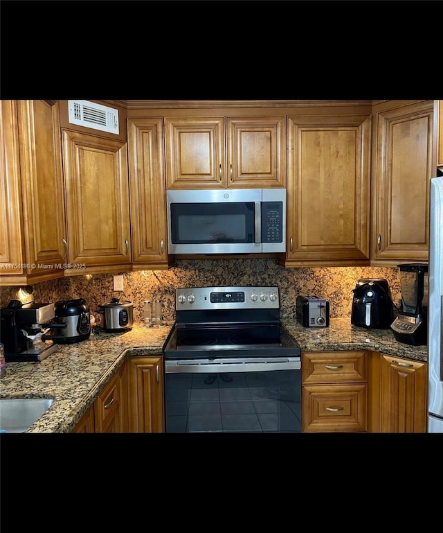 kitchen with appliances with stainless steel finishes, tile patterned flooring, visible vents, and decorative backsplash