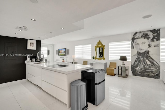 kitchen with black electric stovetop, white cabinetry, a sink, modern cabinets, and a peninsula