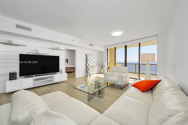 living area with wood finished floors, visible vents, and floor to ceiling windows