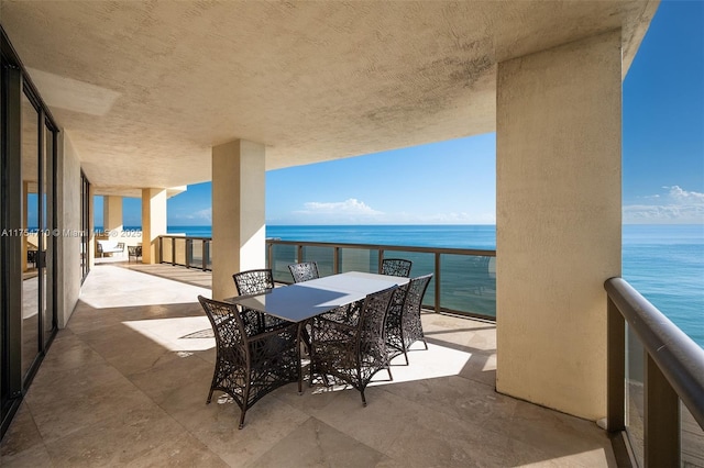 balcony with outdoor dining area and a water view