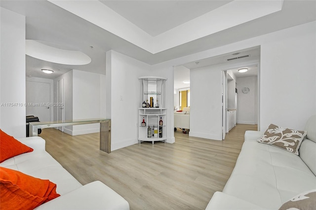 living area featuring visible vents, light wood-style flooring, and baseboards